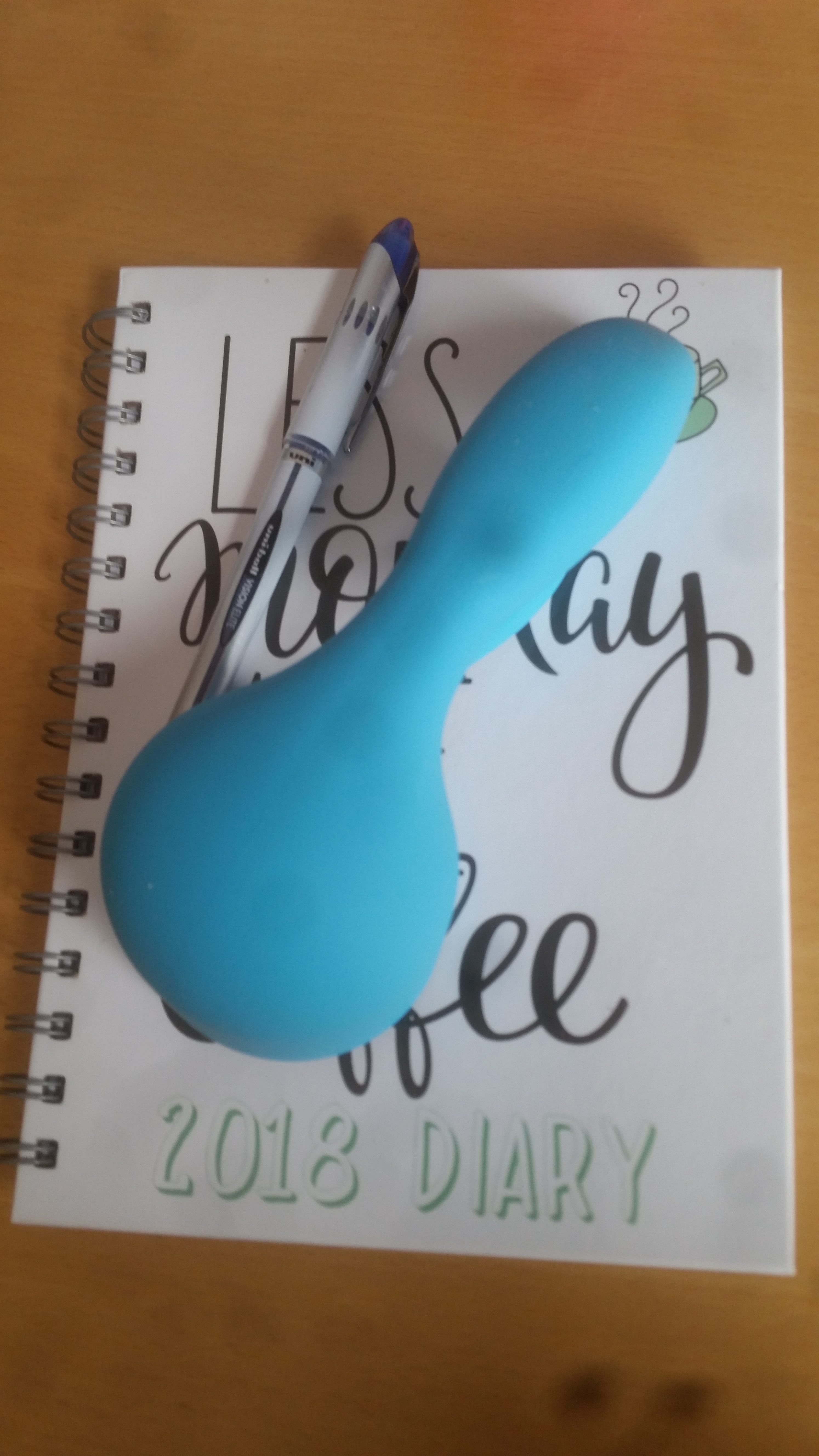 The bodywand rabbit wand attachment made of blue silicone sitting on top of a diary and pen on my desk.