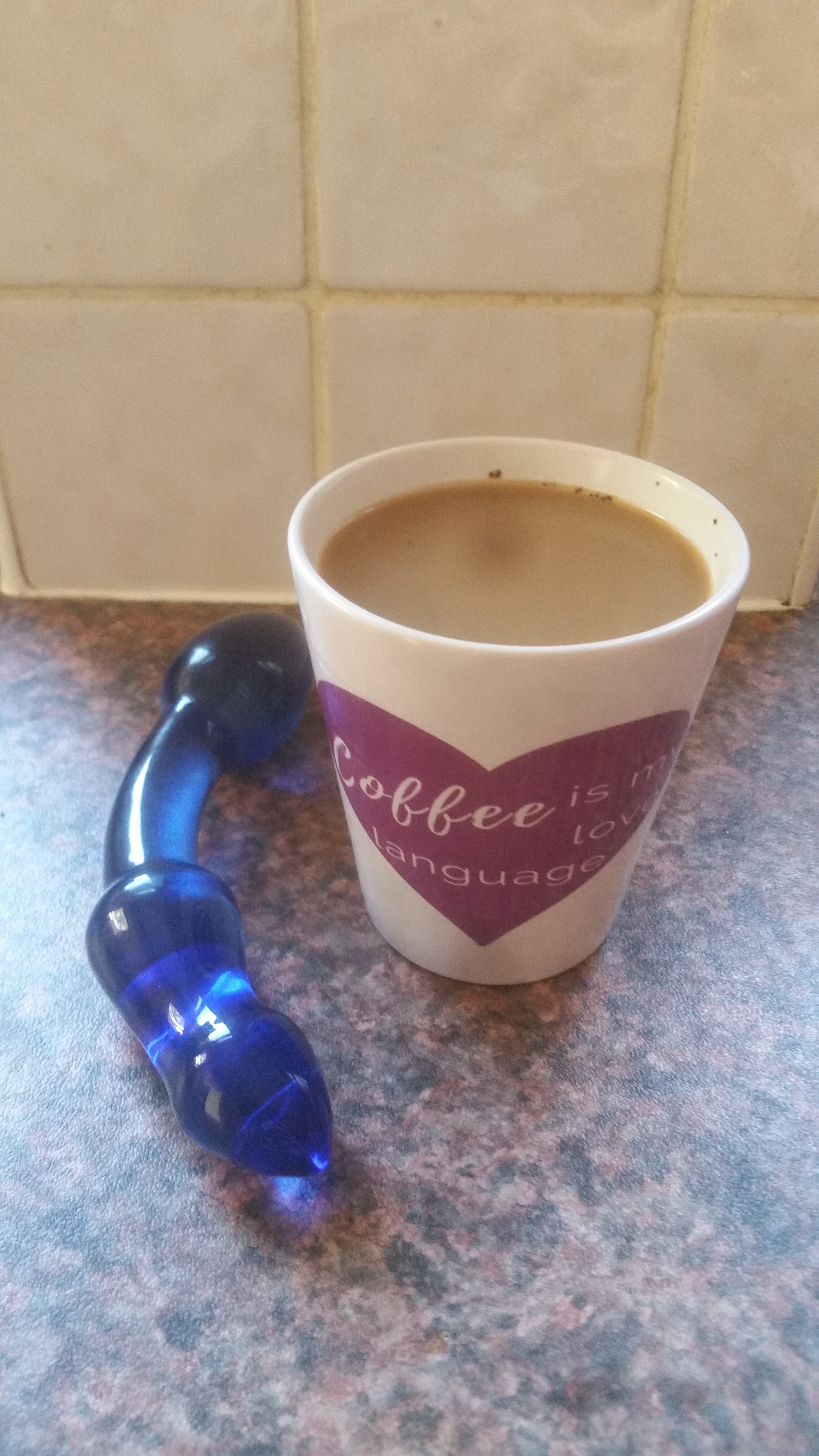 The Chrystalino blue glass double-ended dildo on my kitchen counter with a "Coffee is My Love Language" mug.