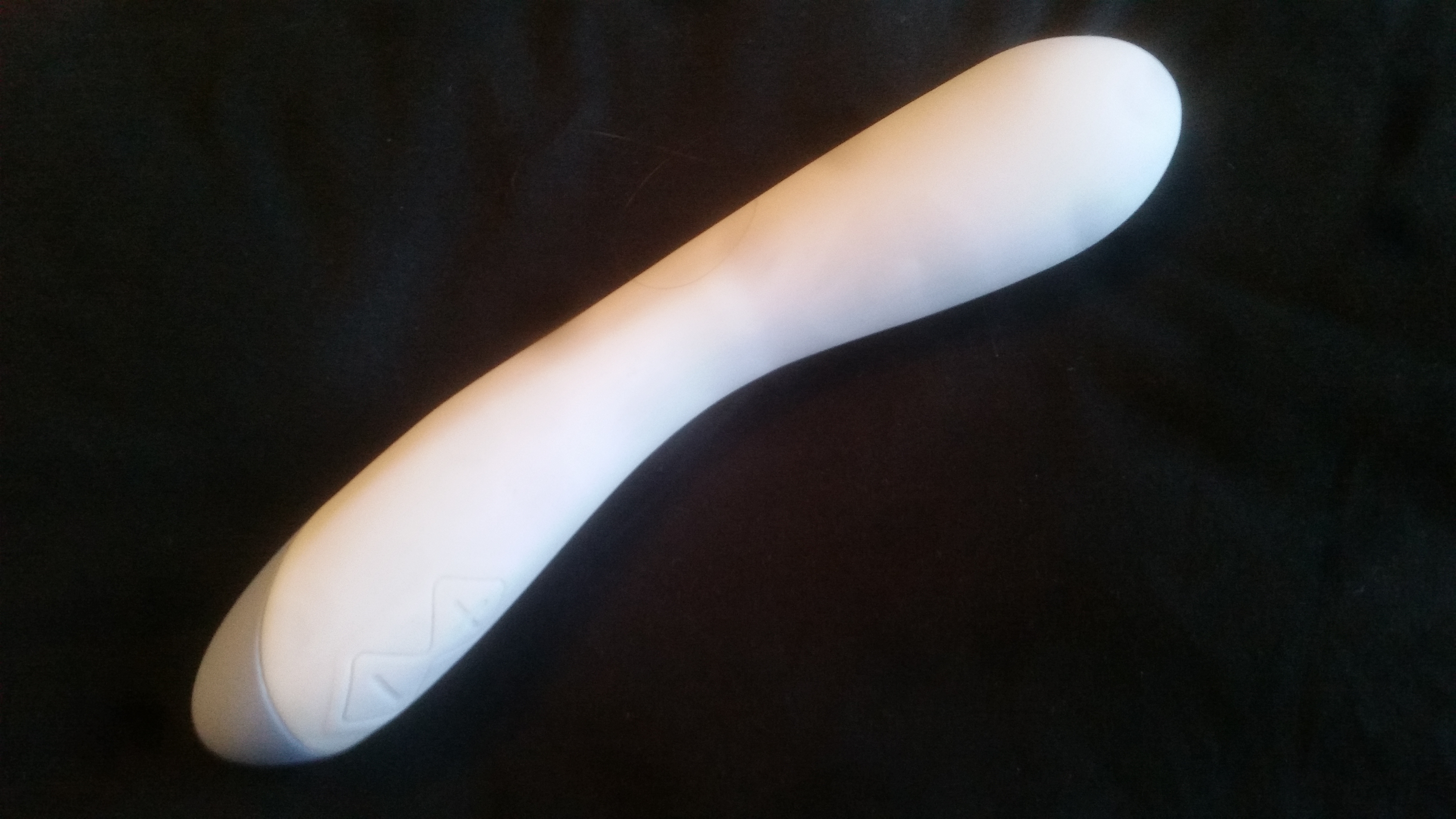 The Sola Cue blue vibrator lying on a black pillow.
