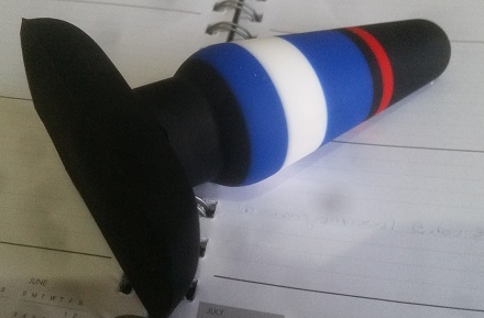 The Power Play butt plug in white blue black and red, lying on an open diary