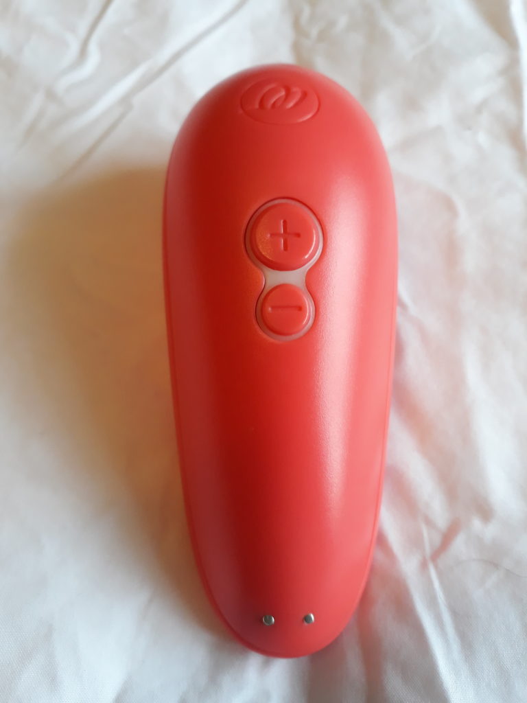 The Womanizer Starlet 2 sex toy in coral on a white sheet