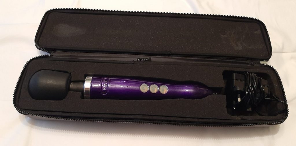 The Doxy Die Cast Wand Massager in purple in its case