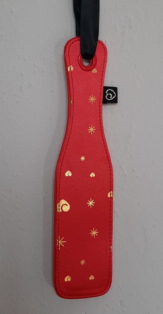 Lovehoney spanking paddle for BDSM hanging on wall